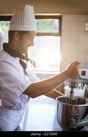 Lo Chef miscelando la pastella nella miscelazione del frullatore Foto Stock