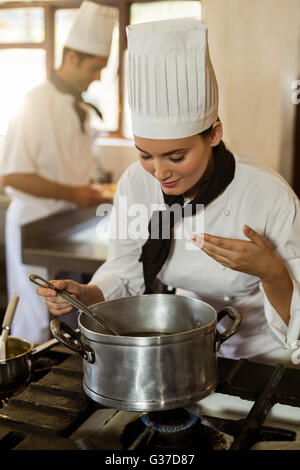 Sorridente capo chef agitazione nel recipiente di cottura Foto Stock