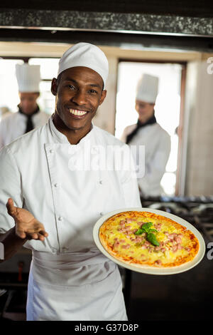 Ritratto di chef sorridente che mostra la pizza Foto Stock