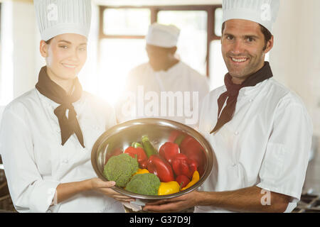 Ritratto di due chef sorridente tenendo una tazza di verdura Foto Stock