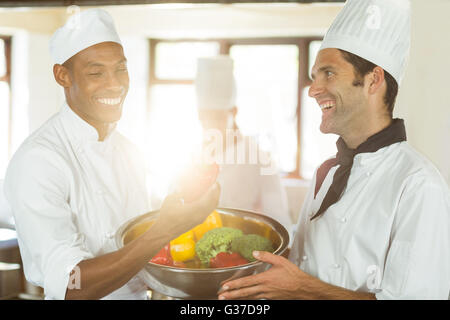 Due chef sorridente tenendo una tazza di verdura Foto Stock