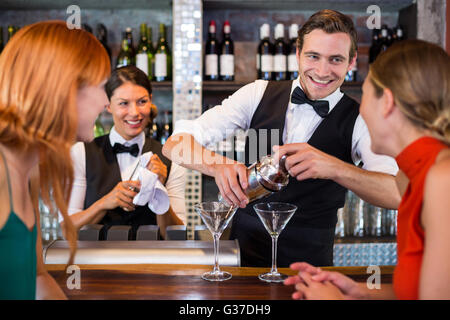 Amici permanente al contatore mentre il barista preparare una bevanda Foto Stock