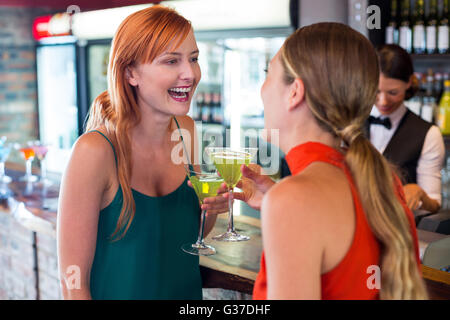 Happy amici tenendo un cocktail nella parte anteriore del banco bar Foto Stock