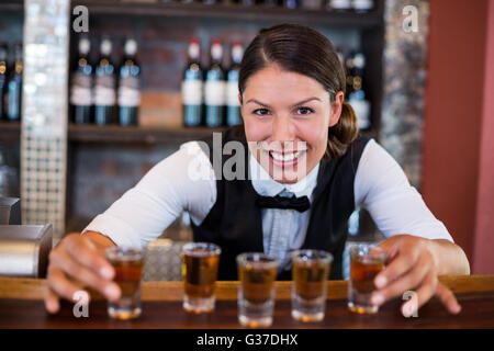 Ritratto di barman immissione bicchierini sul bancone bar Foto Stock