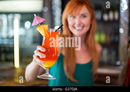 Ritratto di donna felice tenendo un bicchiere da cocktail al bancone bar Foto Stock