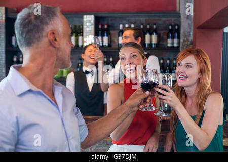 Amici bevendo un bicchiere di vino rosso in un bar Foto Stock