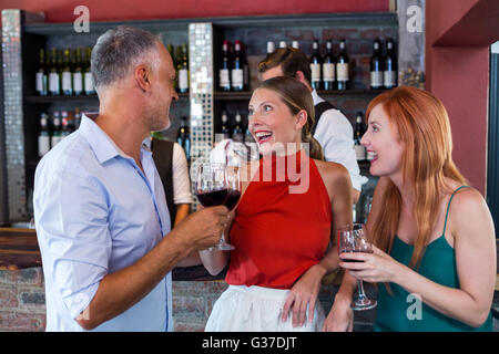 Amici bevendo un bicchiere di vino rosso in un bar Foto Stock