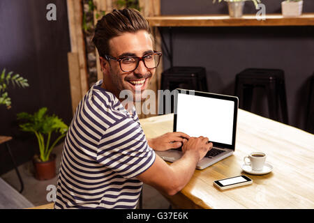 Giovane uomo utilizzando laptop nella caffetteria Foto Stock