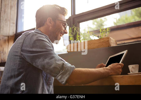 Uomo che utilizza un tablet seduta Foto Stock