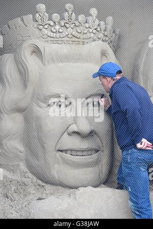 Scultore di sabbia 'Marca Anderson' mette i tocchi di rifinitura per la scultura della regina Elisabetta, Dorset, Regno Unito Foto Stock