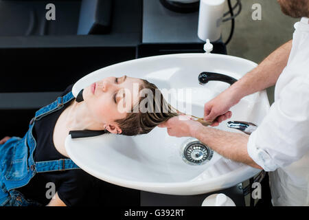 Cura dei capelli nel moderno centro termale salon. Parrucchiere maschio teen di lavaggio la Ragazza capelli Foto Stock