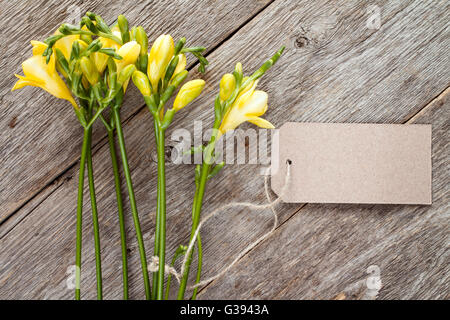 Giallo fresia fiori con tag vuoto sul vecchio sfondo di legno Foto Stock