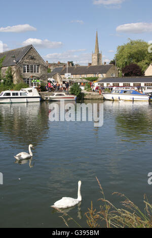 Il Cotswolds. Cigni sul Fiume Tamigi a Lechlade e barche ormeggiate dai Riverside pub. Foto Stock