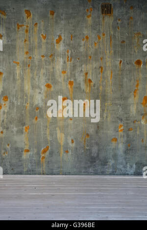 Vecchio verde e marrone e la superficie di parete in calcestruzzo con arrugginita macchie bianche sul pavimento in legno Foto Stock