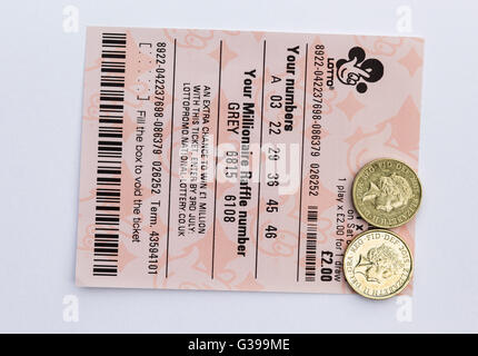 Un due pound UK Lotto ticket con due libbre di monete. Foto Stock