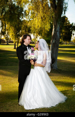 Un americano africano sposa e lo sposo caucasica tenere ogni altro e lo sguardo verso il loro coniuge agli occhi. Così nell'amore. Foto Stock