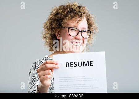 Curly donna su uno sfondo neutro che mostra il suo curriculum Foto Stock