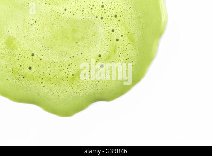 Sfondo di messa a fuoco ravvicinata sulla fusione di tè verde gelato con piccola bolla d'aria sulla superficie. Si fondono e scorrono su sfondo bianco Foto Stock