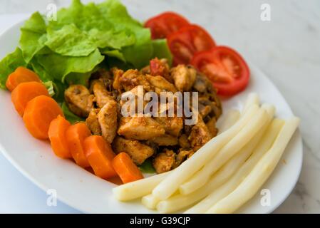 Fritti di carne di pollo servito sulla piastra con asparagi bianchi, carote, pomodori e lattuga. Messa a fuoco selettiva. Foto Stock