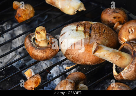 Rosolare gli champignon funghi champignon essendo cotti su char grill con grillmarks Foto Stock