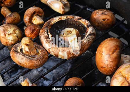 Rosolare gli champignon funghi champignon essendo cotti su char grill Foto Stock