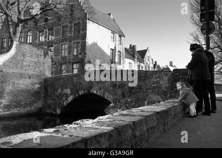 Meebrug: un antico ponte di pietra sul canal Goenerei in fondo Meestraat, Brugge, Belgio: una famiglia guardare l'acqua Foto Stock