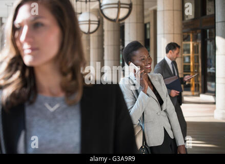 Sorridente corporate imprenditrice parlando al cellulare all'esterno dell'edificio Foto Stock