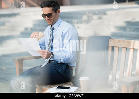 Imprenditore aziendale di mangiare il pranzo e lavorare sul banco di lavoro Foto Stock