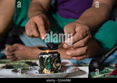 Un abitante di un villaggio si prepara una pallina di oppio per fumatori in Luang Prabang, Luang Prabang Provincia, Laos Foto Stock