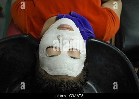 Una giovane donna indossa una maschera per il viso a un salone di bellezza in Ban Watsene, Luang Prabang, Luang Prabang Provincia, Laos Foto Stock