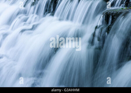 Acqua a cascata su uno stramazzo con motion blur. Tumbling Weir sul fiume Yeo a Wrington, North Somerset, Inghilterra. Foto Stock