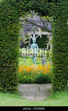 Ragazza statua chiamata "la lampada della saggezza". Giardino ornamentale statua e Wisteria archway nel giardino formale a Waterperry giardini, Oxfordshire, Regno Unito Foto Stock