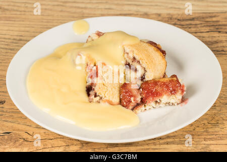 Tradizionale budino britannico di Jam Roly Poly con crema pasticcera Foto Stock