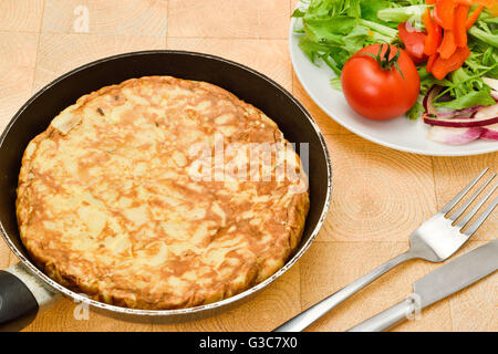 Una frittata spagnola o tortilla servita con pomodoro e insalata verde Foto Stock