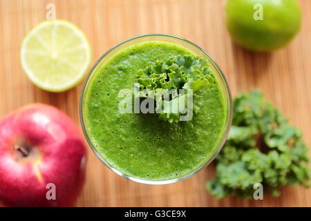 Al di sopra di visualizzare su una lastra di vetro con un sano frullato verde con kale, apple e calce Foto Stock