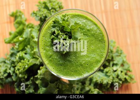 Fresco e sano frullato verde con foglie di cavolo riccio. Angolo di visione su una lastra di vetro Foto Stock