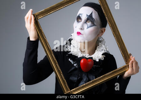 La donna a camuffare la harlequin nella cornice immagine Foto Stock