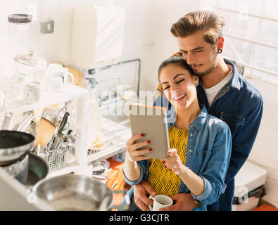 Affettuosa coppia giovane con tavoletta digitale in appartamento cucina Foto Stock