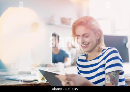Creative sorridente giovane imprenditrice utilizzando tavoletta digitale Foto Stock