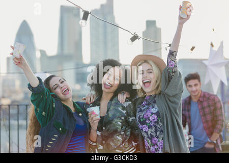 Ritratto di giovane esuberante donne tifo e bere alla festa sul tetto Foto Stock