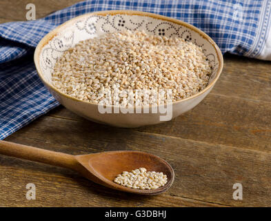 Orzo grezzo nella ciotola su una tavola in legno rustico. Foto Stock