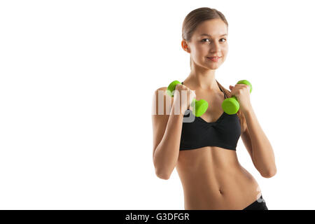 Sorridente donna atletica pompando i muscoli con manubri su sfondo bianco Foto Stock