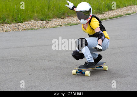 Donna in discesa guidatore di skateboard nel casco con oscurati visiera Foto Stock