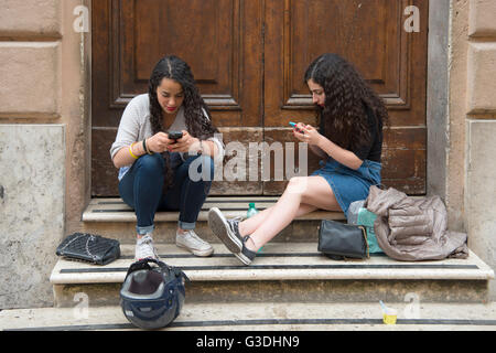 Italien, Rom, Via del Portico d'Ottavia, giovani ragazze con lo smartphone Foto Stock