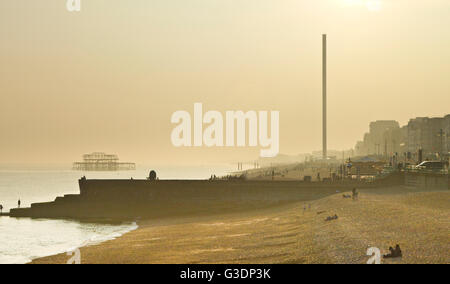 Haze dalla tarda sera sun si ammorbidisce i contorni del Molo Ovest e la colonna dell'i360 sul lungomare di Brighton Foto Stock