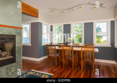 Zona pranzo tavolo e sedie con pavimenti in legno, pareti dipinte, illuminazione d'accento & windows vista in contemporaneo ed elegante arredamento Foto Stock