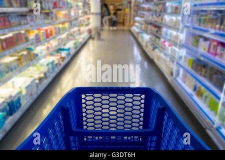Carrello acquisti in un supermercato con ripiani sfocata in background Foto Stock