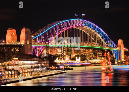 Illuminato arch lato del punto di riferimento il Ponte del Porto di Sydney dopo il tramonto che riflettono luci nel ancora sfocata acque della baia. Foto Stock