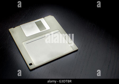 Grigio disco floppy vuoto etichetta con legno nero sfondo scrivania Foto Stock