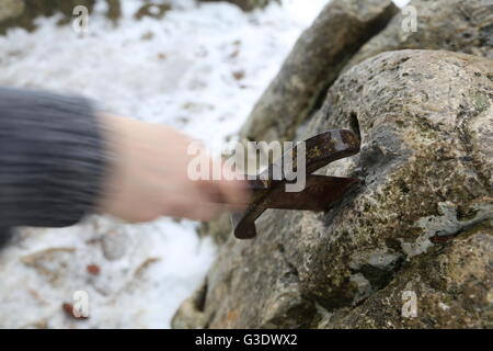 Mano del prode cavaliere tenta di rimuovere la magica Excalibur spada nella roccia Foto Stock